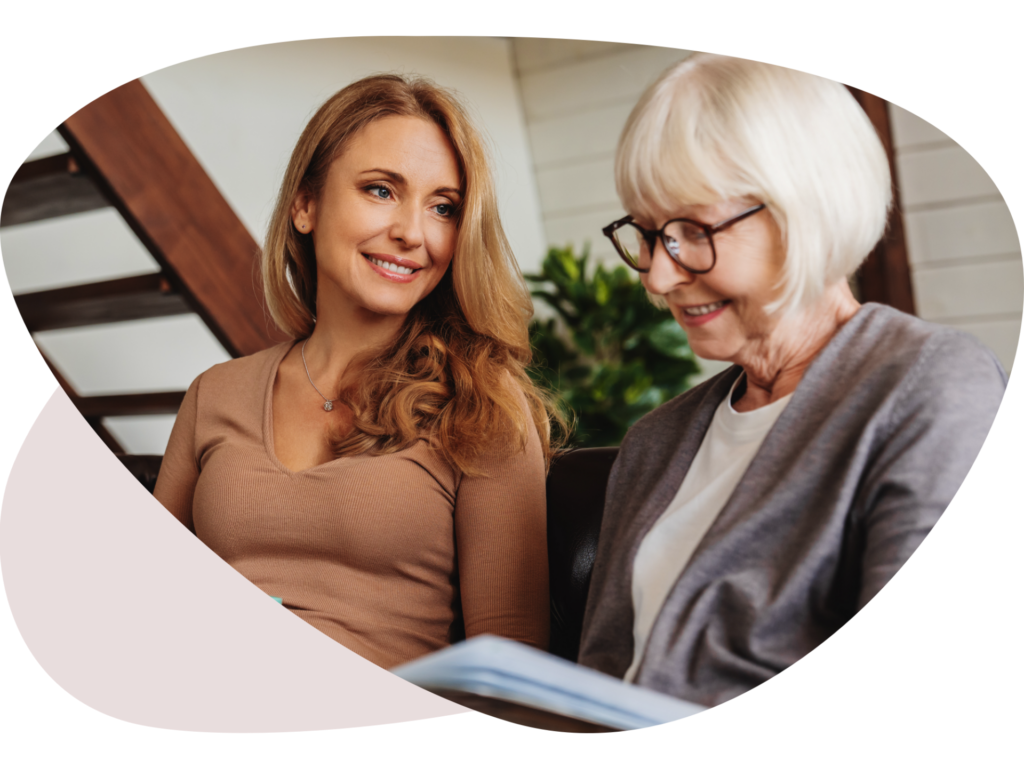 Two women smiling and reading a book